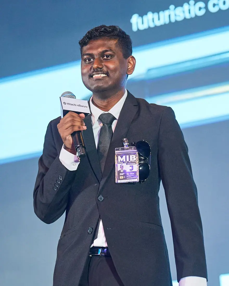 Jonathan speaking on stage with a microphone at a Hitachi eBworx event
